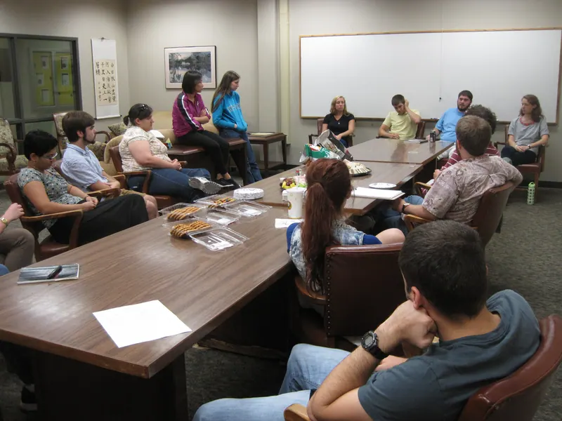 Attendees gather around the Keisler Lounge table to listen to the presenters.