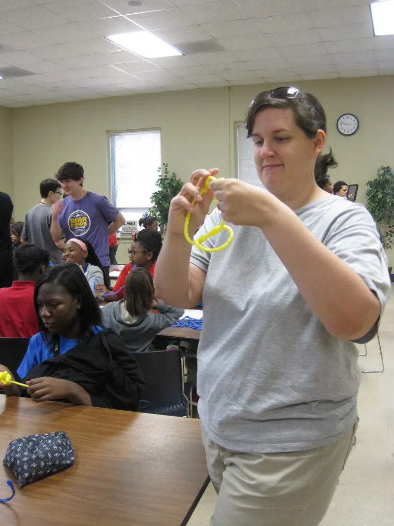 A volunteer twists some yellow string.