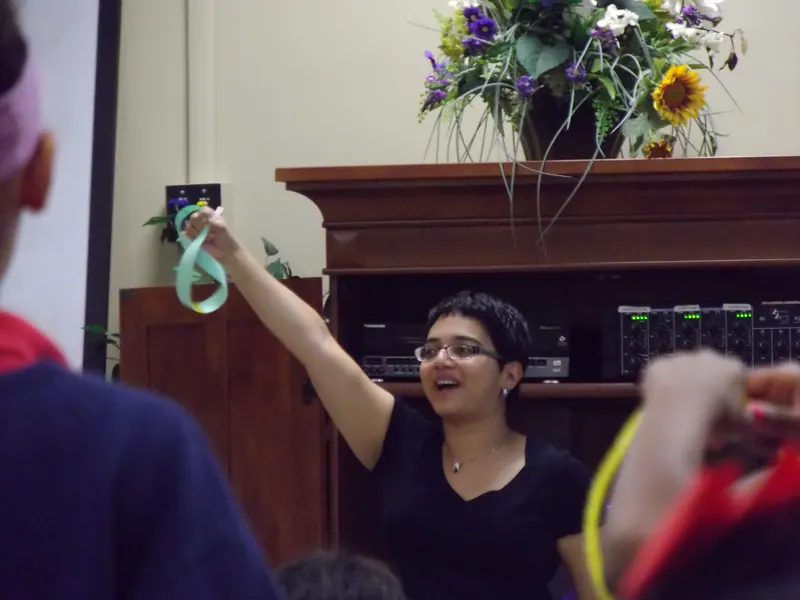A volunteer triumphantly holds up a green-cardstock Möbius strip.