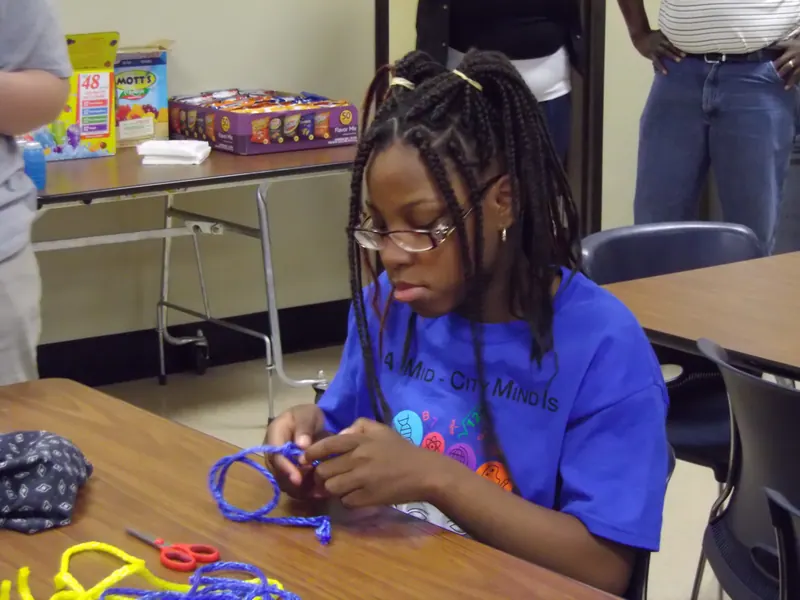 A child calmly works on a length of blue string.