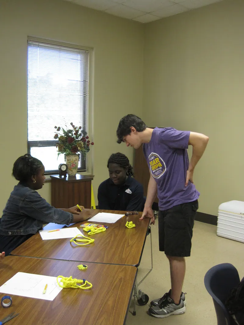 Two students discuss their knots with a volunteer.
