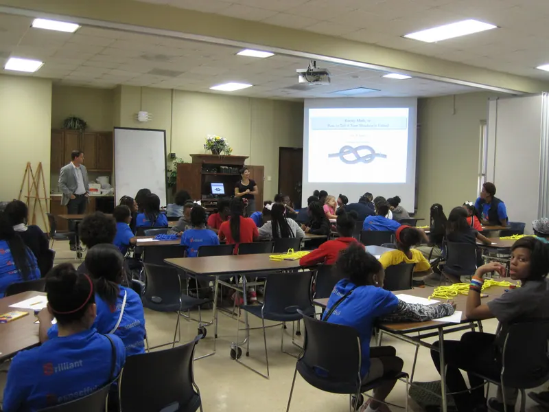 Members begin a presentation titled 'Knotty Math, or: How to Tell if Your Shoelace is Untied' to the gathered children.