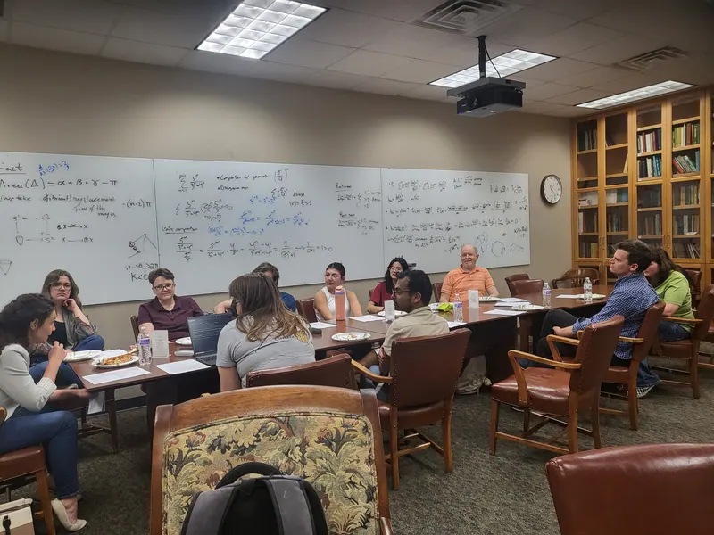 The table is populated by attendees and slices of pizza listening to Amber Schreve talk.