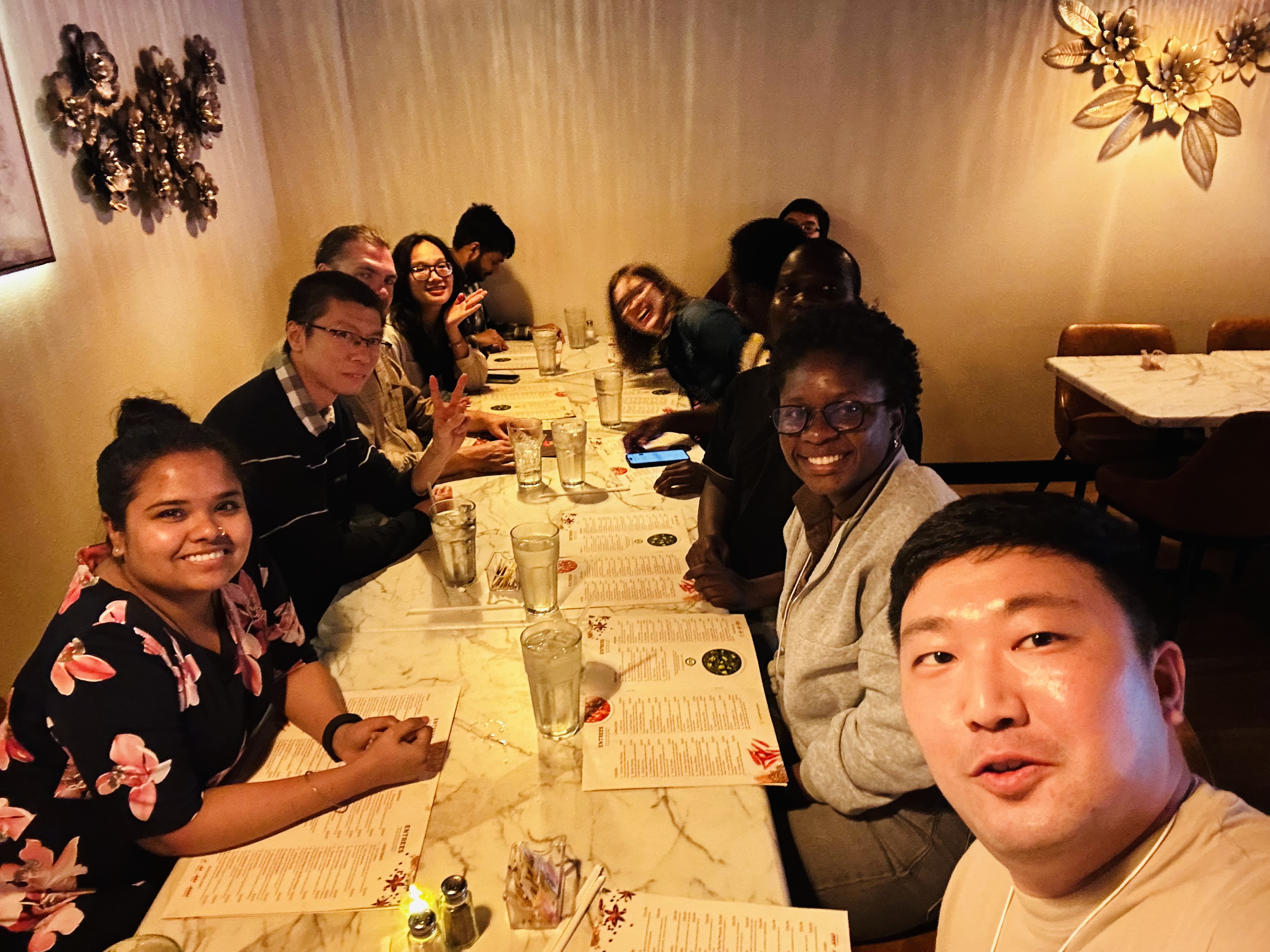 Students attending the SCALA conference at LSU take a group photo while reading menus at a restaurant dining table.