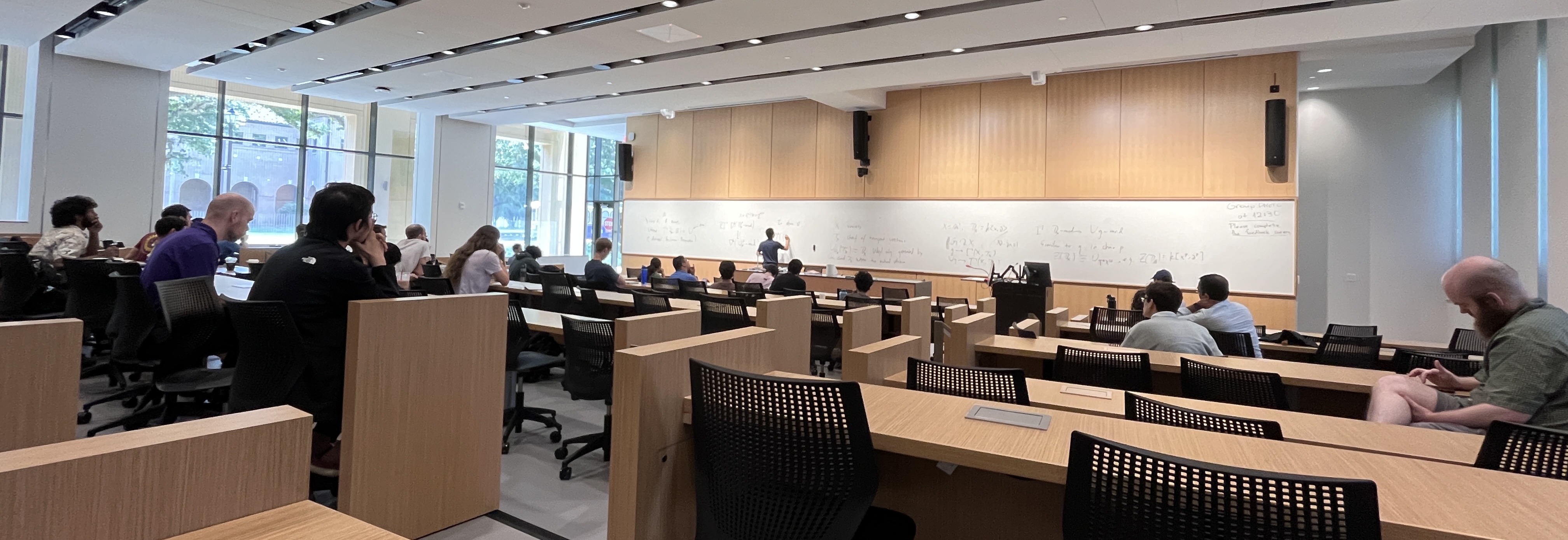 A large lecture hall with a mathematics presentation ongoing.